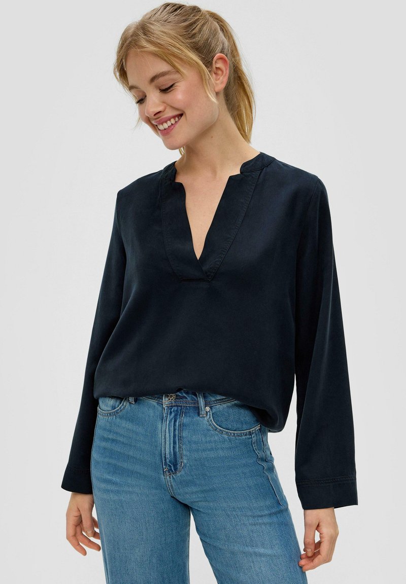 Marineblauw blouse met lange mouwen en V-hals, gemaakt van een gladde stof. Heeft een relaxte pasvorm en subtiele stiksels. G gecombineerd met blauwe jeans.