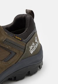 Talons de chaussures de randonnée marron et noir avec semelle texturée, col rembourré, logo "Jack Wolfskin" et petite étiquette en tissu "TEXAPORE".