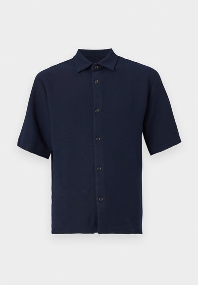 Μπλε ναυτικού χρώματος πουκάμισο με κοντά μανίκια και κουμπιά, με γιακά, που διαθέτει υφή υφάσματος και πέντε μαύρα κουμπιά στο μπροστινό μέρος.