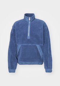 Blå fleecepulli med hög krage, halv dragkedja fram, texturerad kropp och släta tygdetaljer. Har framfickor och ribbade ärmslut.