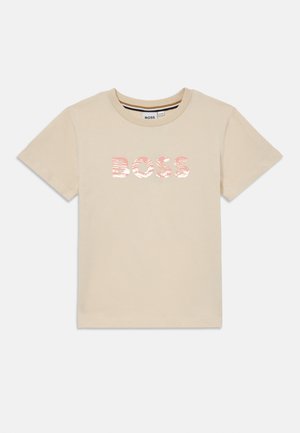 Šviesiai ruda medvilninė marškinėliai trumpomis rankovėmis, su apvaliu kaklu, priekyje su tekstūruotu rožiniu "BOSS" logotipu. Paprastas, subtilus dizainas.