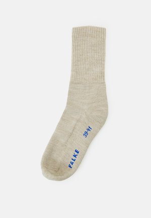 Beige gerippte Socke aus weichem Material mit runder Zehenpartie und einem blauen Logo mit Größenangaben, das an der Seite aufgedruckt ist.