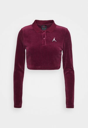 Burgundy lyhyet hihat, napsuttava polo-paita, joka on valmistettu corduroykankaasta; siinä on ribbikuvio ja valkoinen logo rinnassa.