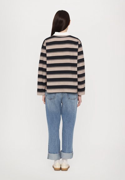 Stripet langermet topp i beige og marineblå, krage med rett snitt. Brukt med lyseblå denim jeans med oppbrett og hvite sko.