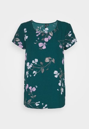 Blouse vert foncé à manches courtes avec col rond, présentant un motif floral en blanc, rose clair et feuilles et branches marron.