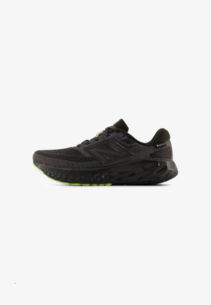 Schwarzer New Balance Laufschuh mit strukturierter Sohle, Mesh-Obermaterial, Gore-Tex-Label und neon-grünen Akzenten auf der Laufsohle und dem Logo.
