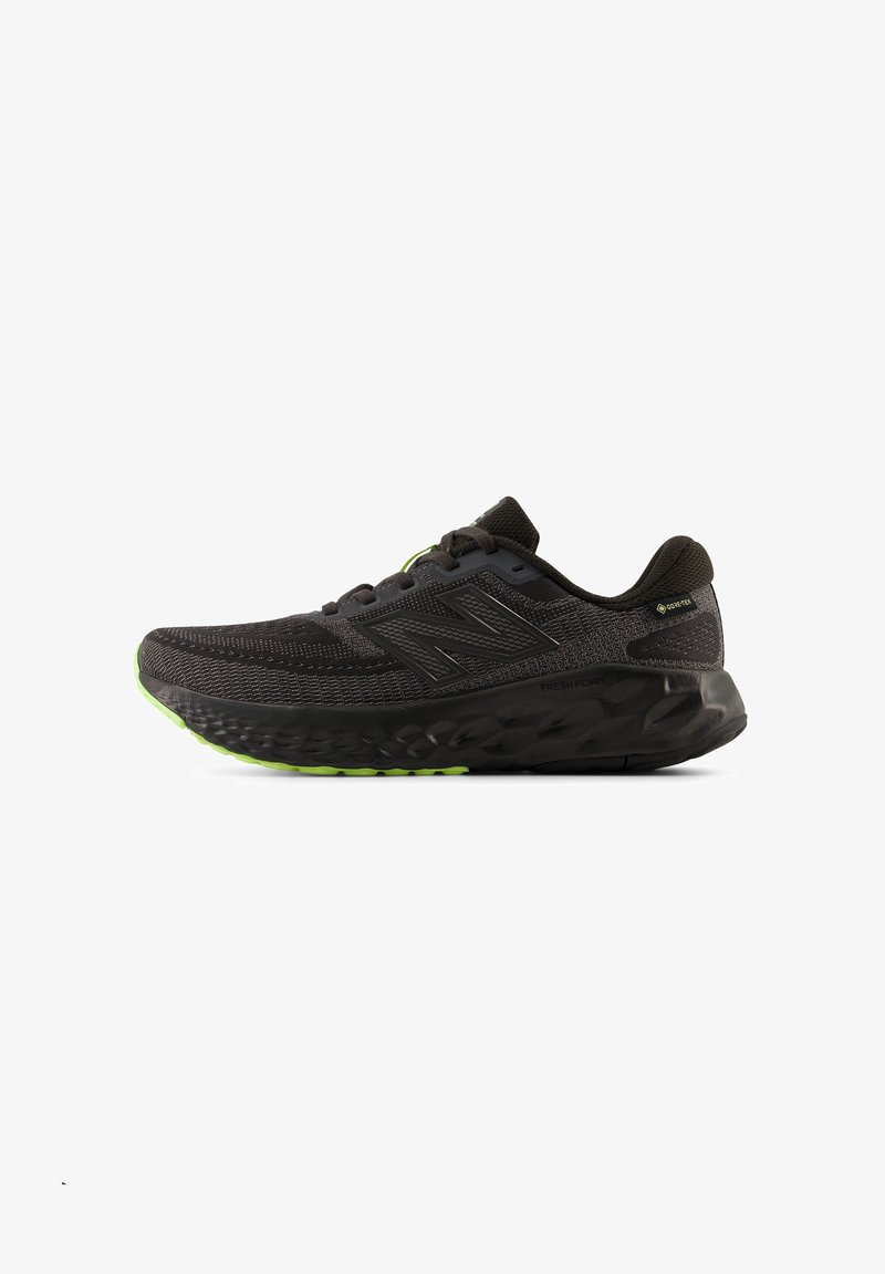 Μαύρο παπούτσι για τρέξιμο New Balance με υφή στη σόλα, επάνω μέρος από δίχτυ, ετικέτα Gore-Tex και νεονίζον πράσινες λεπτομέρειες στη σόλα και το λογότυπο.