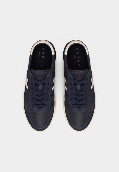 Ζευγάρι αθλητικά παπούτσια δαντέλας σε ναυτικό μπλε και λευκό χρώμα με λεπτομέρειες από σουέντ και δέρμα, σε θέα από πάνω σε λευκό φόντο.