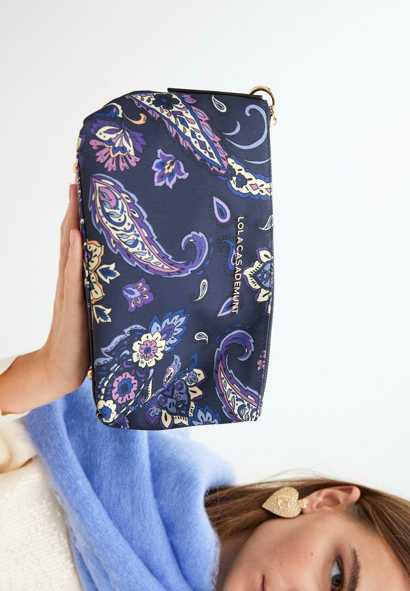 Mornarska kozmetička torbica s mnoštvom floralnih paisley uzoraka u raznim bojama, s zlatnim patentnim zatvaračem i malim logotipom. Glatka tkanina s čvrstim oblikom.