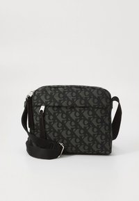 Svart skulderveske med et teksturert mønster av initialer, justerbar rem, glidelåslukking og sølvsfarget metallbeslag. Kompakt, rektangulær form.