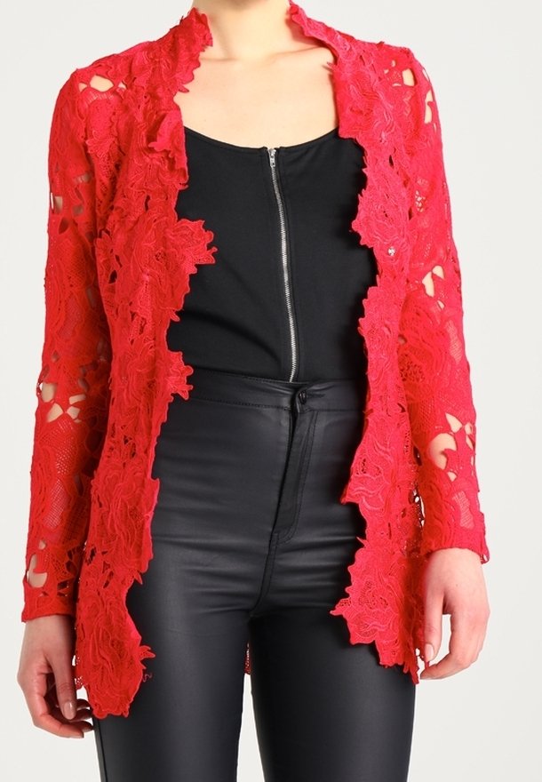 Cardigan long à manches longues en dentelle florale rouge porté ouvert sur un haut noir à fermeture éclair devant, associé à un pantalon en cuir noir taille haute.