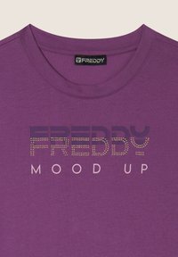 T-shirt in cotone viola con scollatura rotonda. Presenta una stampa con la parola "FREDDY" in pietre metalliche, con la frase "MOOD UP" sotto in rosa chiaro.