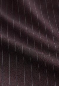 Dunkelburgunderfarbener Stoff mit feinen, senkrechten, hellgrauen Nadelstreifen. Glatte Textur mit einem leicht strukturierten Webmuster.