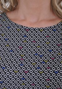 Zwart patroonstof met witte diamantvormen en kleurrijke accenten in roze, geel en blauw. Ronde halslijn, gladde textuur.