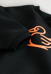Sort sweatshirt med en orange and grafisk. Har ribbede manchetter og halsudskæring, blød tekstur og et afslappet design.
