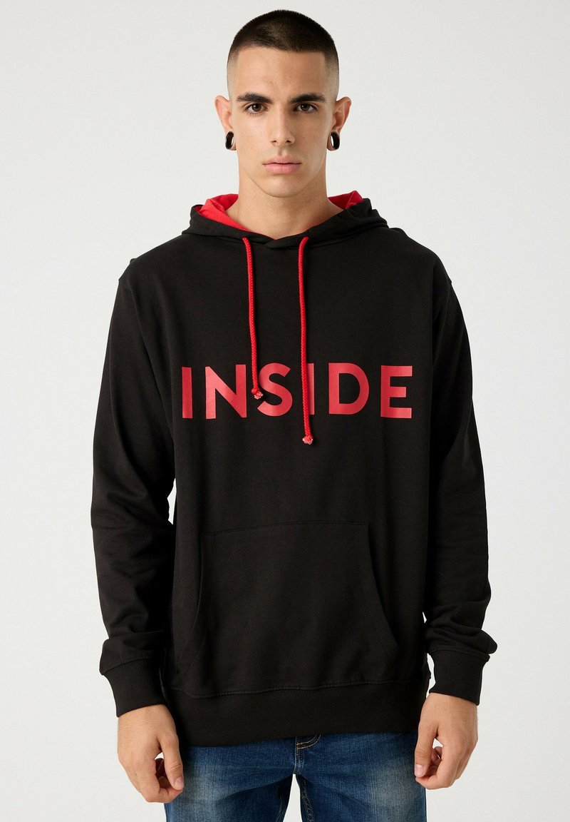Sudadera con capucha de tejido negro que presenta un gran gráfico rojo con la palabra "INSIDE", detalles rojos y un bolsillo frontal. Los cordones son rojos.