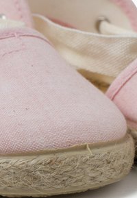 Růžové plátěné espadrilky s jutu rope podrážkou, s texturovaným povrchem a látkovým páskem. Hladké okraje a jednoduchý design.