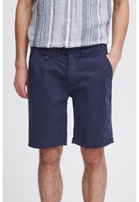 Shorts en coton bleu marine avec une taille plate, deux poches latérales et une fermeture à bouton. Dotés d'une coupe classique et d'un ourlet.