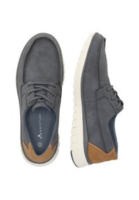 Chaussures en suède gris avec une semelle en caoutchouc blanc, présentant un accent en cuir marron et des lacets gris. Design à bout rond et semelle intérieure rembourrée.
