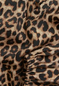 Leopardprint stof met een glanzende afwerking; presenteert bruine, zwarte en tan tinten in een kenmerkend patroon; zachte textuur met geruwde randen.