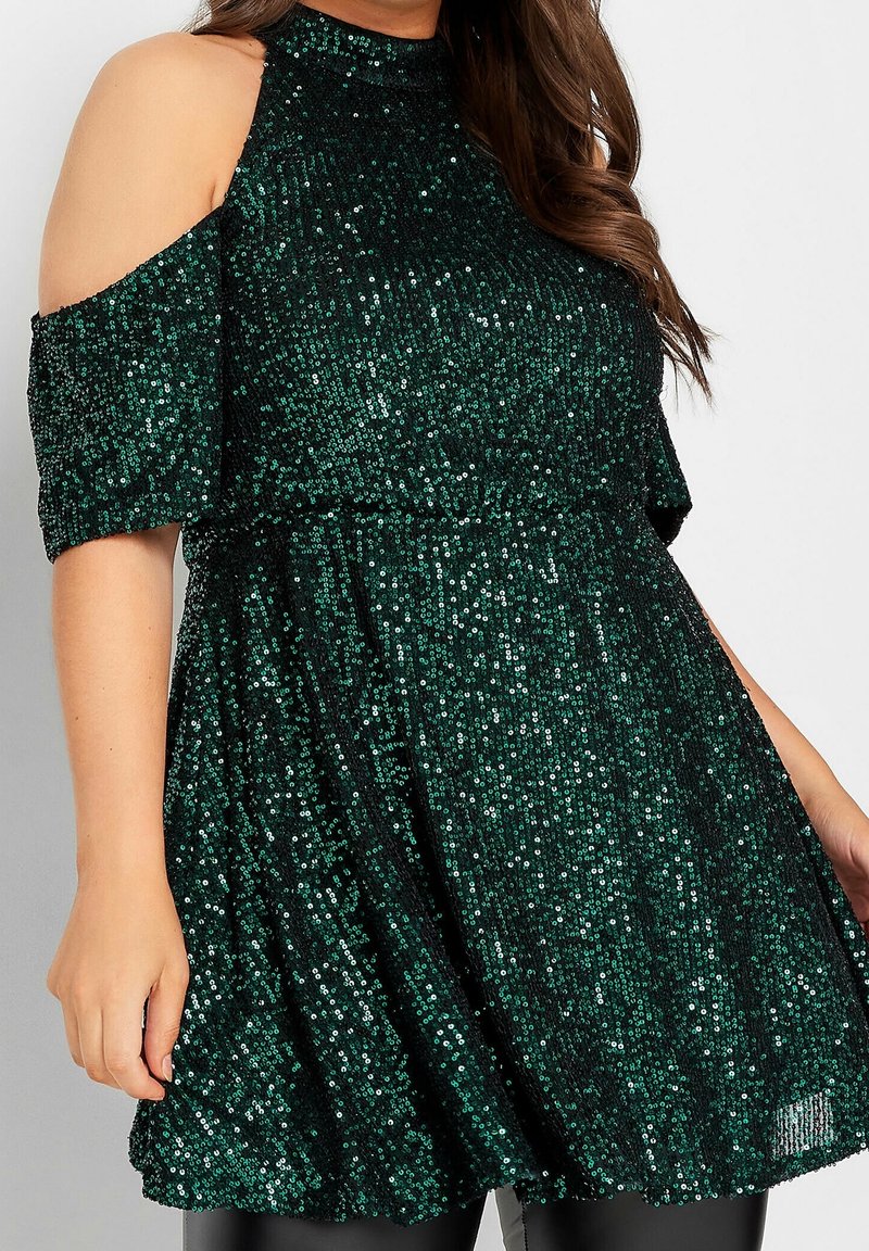 Robe verte à sequins avec manches épaules dénudées, col montant, taille cintrée et jupe évasée. Texture brillante avec des sequins scintillants sur toute la surface.