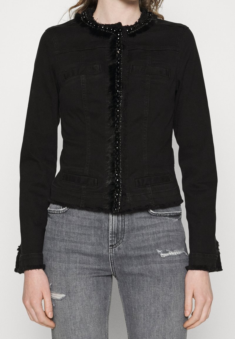Svart denimjacka med en figursydd design, dekorativt pärl- och pälskrage, framfickor och slitna manschetter.