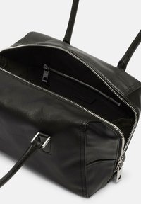 Schwarz Ledertasche mit Reißverschluss-Oberseite, zwei Griffen und einem geräumigen Innenraum. Enthält Futter und eine innere Reißverschlusstasche. Silberne Hardware-Details.