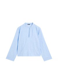 Blouse bleu clair à manches longues avec un col rond et une fente à l'avant. Fabriquée en tissu texturé, elle présente une coupe large et courte.