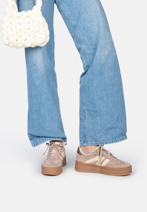 Baskets avec une tige en suede marron clair, des accents beiges, un bout rond et une semelle épaisse en cuir marron ; assorties à un jean large bleu délavé et à un sac tressé blanc.