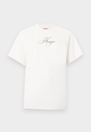 T-shirt bianca a maniche corte con scollo tondo e logo "Hugo" stampato in nero e oro al centro del petto.