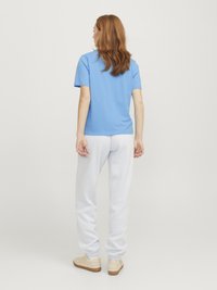 Ljusblå kortärmad t-shirt som matchas med vita sweatpants, med elastiska muddar och en avslappnad passform. Beiga sneakers fulländar looken.