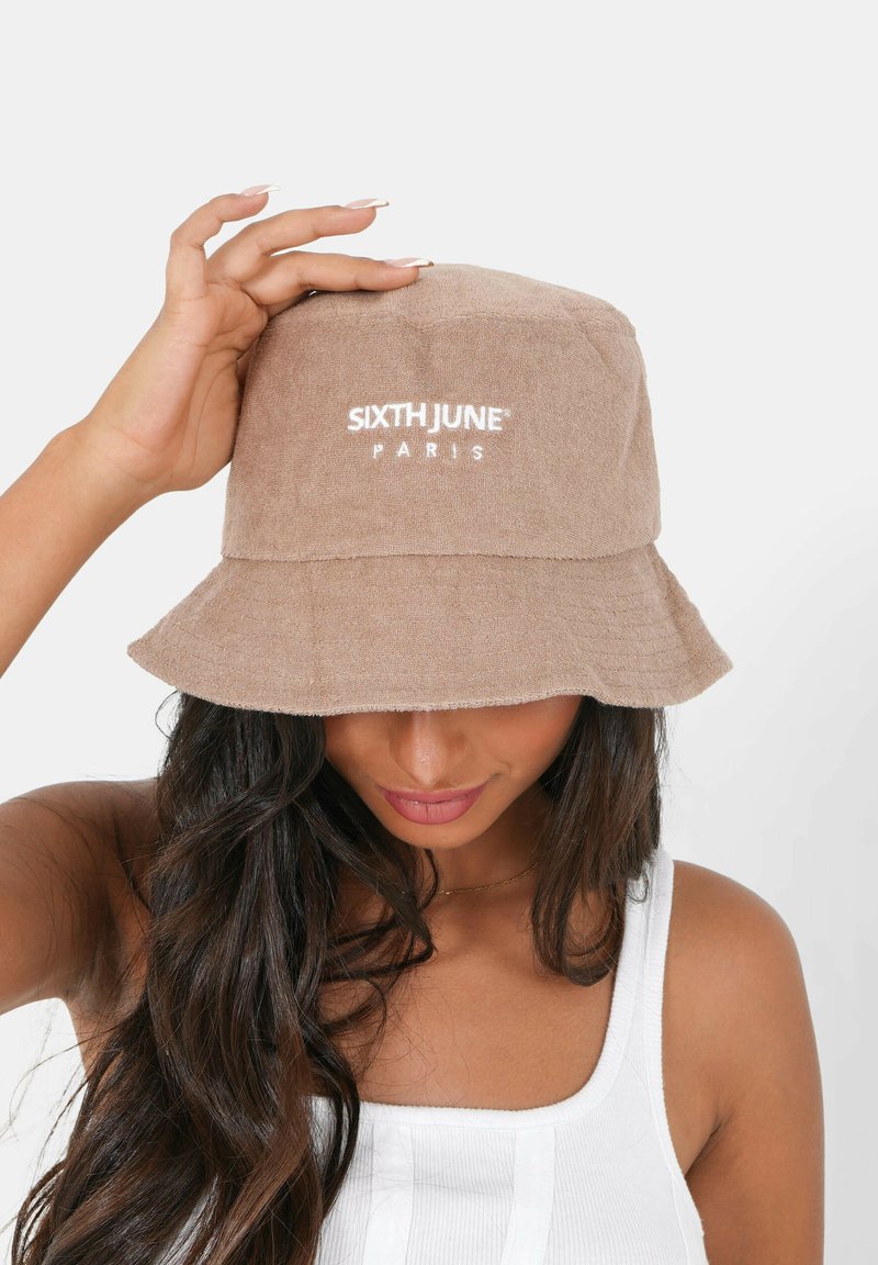 Cappello a secchiello marrone realizzato in tessuto testurizzato, con il logo bianco "SIXTH JUNE PARIS" sul davanti. Ampia visiera inclinata verso il basso.