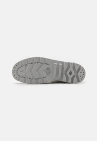 Grey rubber shoe sole featuring a textured tread pattern and reinforcement details. Designed for grip and durability with drainage holes.