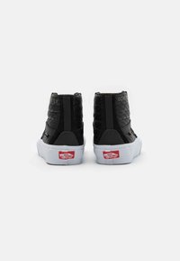 Sneakers alte nere con texture trapuntata. Presentano una suola bianca, marchio GORE-TEX e logo rosso Vans. Aree della punta e del tallone rinforzate.