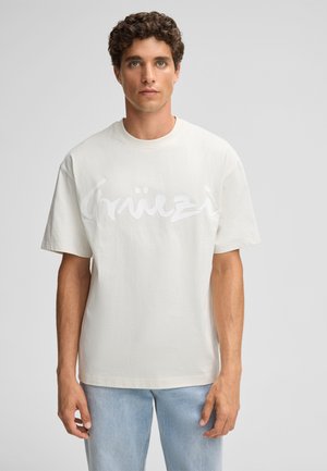 White cotton T-shirt featuring a large printed logo in a slightly darker shade. The shirt has a relaxed fit and short sleeves.