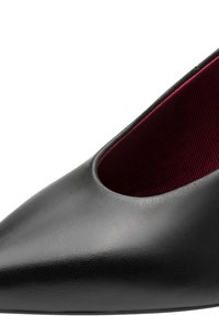 Chaussure en cuir noire à bout pointu avec une doublure intérieure rouge foncé texturée visible le long de l’ouverture.