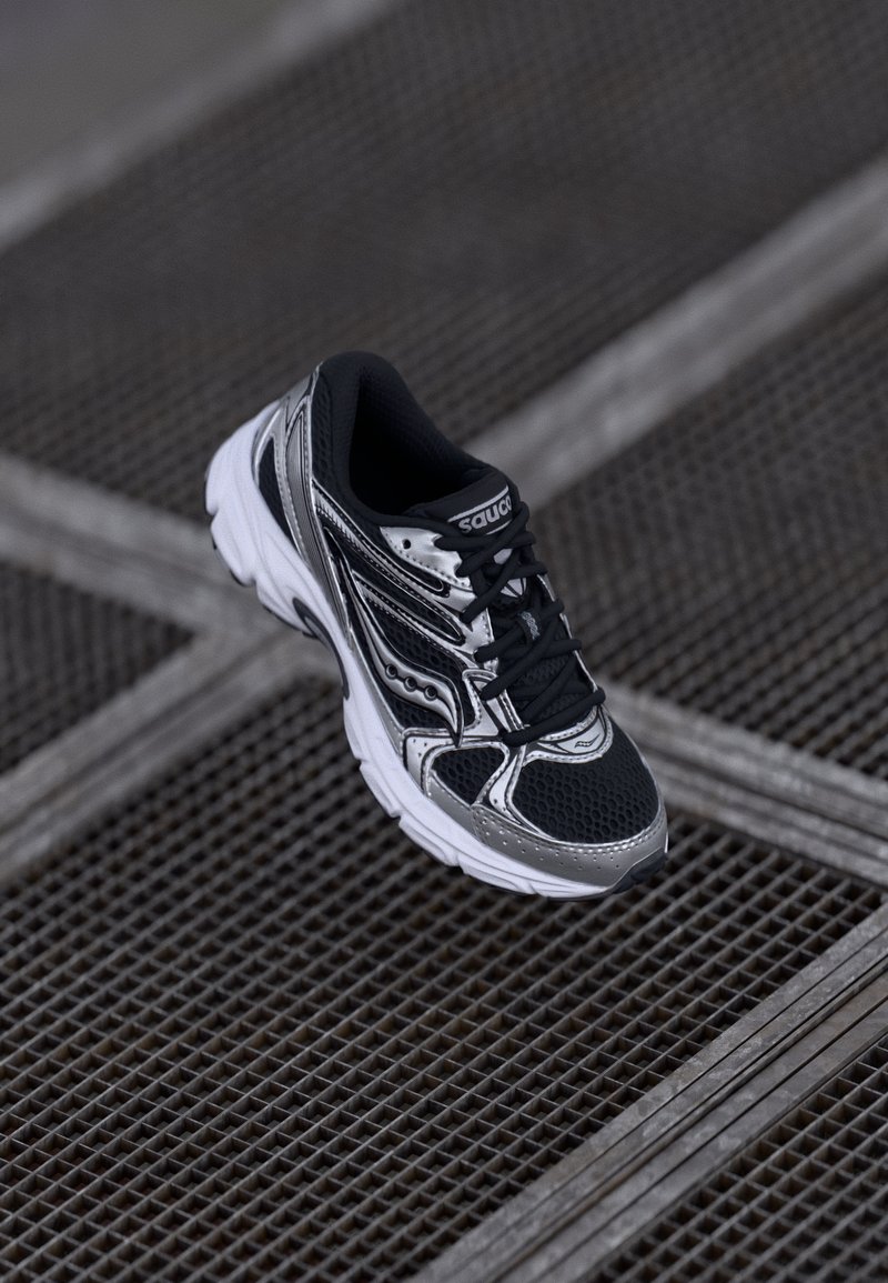 Black and silver running shoe with a mesh upper, textured detailing, and a cushioned sole, featuring black laces and logo embossed on the tongue.
