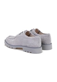 Chaussures en suède gris avec une forme arrondie, un piquage détaillé et une épaisse semelle en caoutchouc gris présentant un motif texturé. Lacets de couleur sombre.