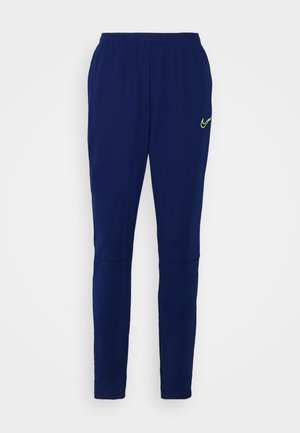 Marineblauwe sportbroek met elastische tailleband en geel Nike-logo op de bovenste linker dij, platliggend tegen een witte achtergrond.