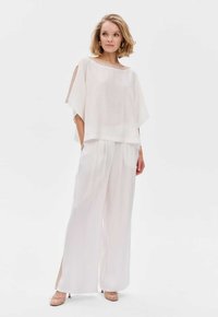 Witte lichtgewicht twee-delige outfit met een losse, korte mouw top en wijde broek, met een gladde textuur en minimalistisch design.