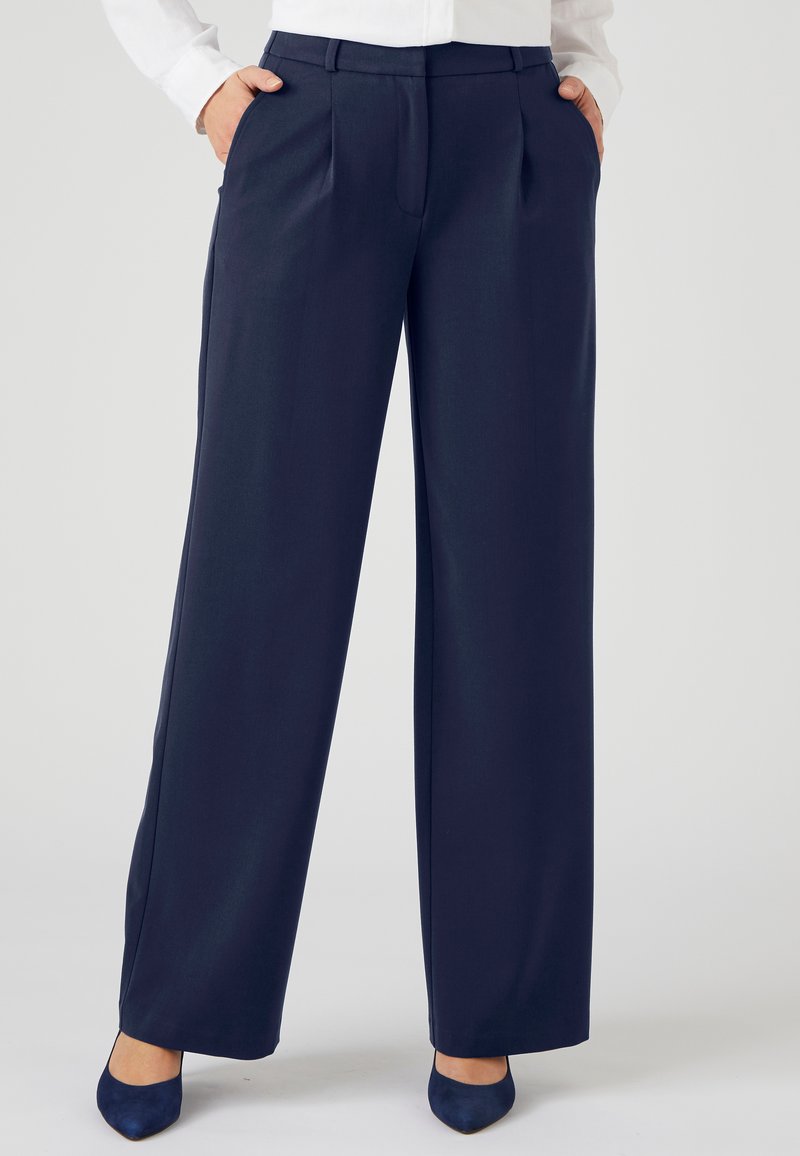 Marineblauwe wijde broek met plooien, zijzakken en een gladde textuur. Gemaakt in combinatie met bijpassende marineblauwe stiletto's. Op maat gemaakt voor een klassieke pasvorm.