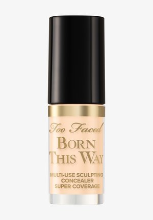 Too Faced Born This Way multifunctionele sculpting concealerfles met zwarte dop en gouden letters op een beige achtergrond.