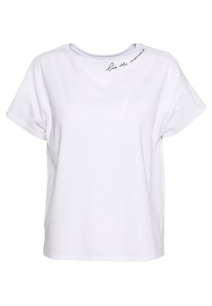 T-shirt blanc à manches courtes avec un col rond et un petit texte cursif noir indiquant "vis la moment" près du col sur le côté gauche.