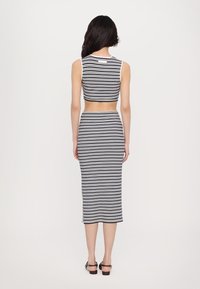 Stripet crop top og matchende midi-skjørt i navy og hvit. Materialet ser mykt ut, med en kroppsfasong og sidespalter på skjørtet.