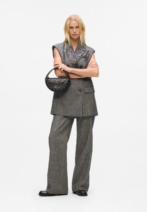 Gray tailored outfit featuring a short-sleeve blazer and wide-leg pants, with a sequined black handbag and studded black shoes.