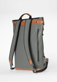 Grauem Rucksack mit braunen Lederakzenten, gepolsterten Tragegurten, einer seitlichen Reißverschlusstasche und einem oberen Griff für einfaches Tragen. Strapazierfähige Stofftextur.