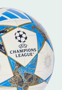 Fodbold med blå og gyldne stjernemønstre, der viser UEFA Champions League-logoet samt stiliserede fiske- og solillustrationer.