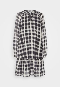 Robe à carreaux noir et blanc avec un ourlet volants, manches longues, encolure froncée et un détail à nouer au col, faite en tissu léger.