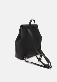 Sac à dos en cuir noir avec bretelles réglables et poignée de transport supérieure sur fond blanc.