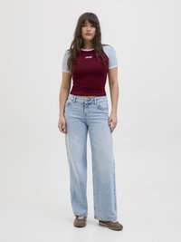 Burgunderfarget og lyseblå kortermet tettsittende topp med "1998" trykt i hvitt; høy midje lyseblå vide jeans; brune sko.